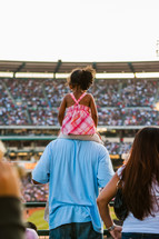 Young girl sitting on father shoulders at crusade dad 