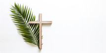 Palm Sunday. Wooden cross and palm leaf on white background with copy space.
