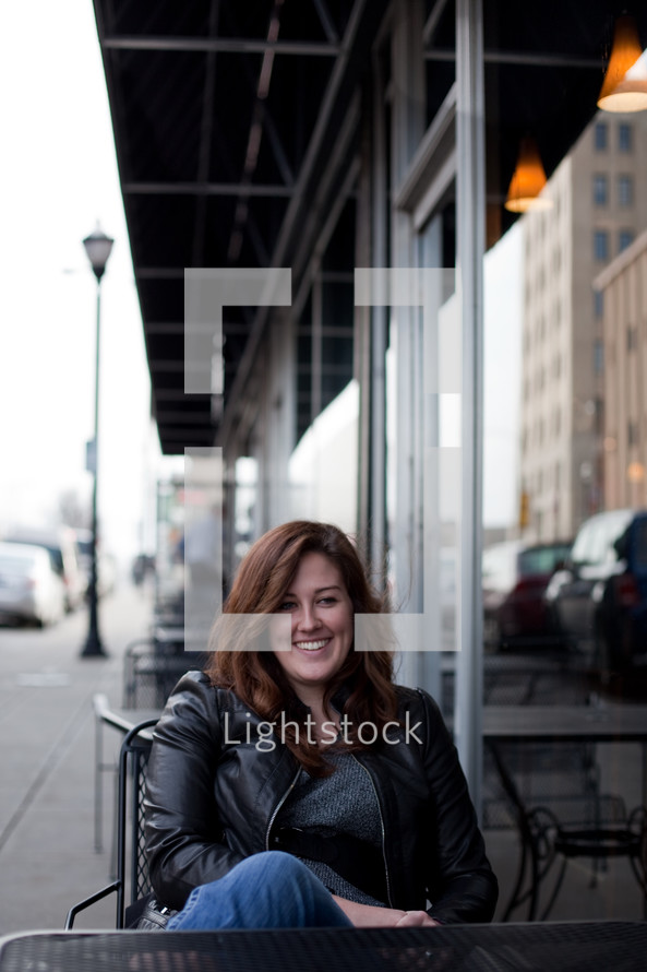 smiling woman sitting at an outdoor table 