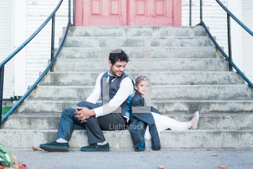 father and daughter sitting on church steps 