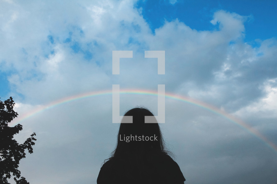 silhouette of a child under a rainbow 