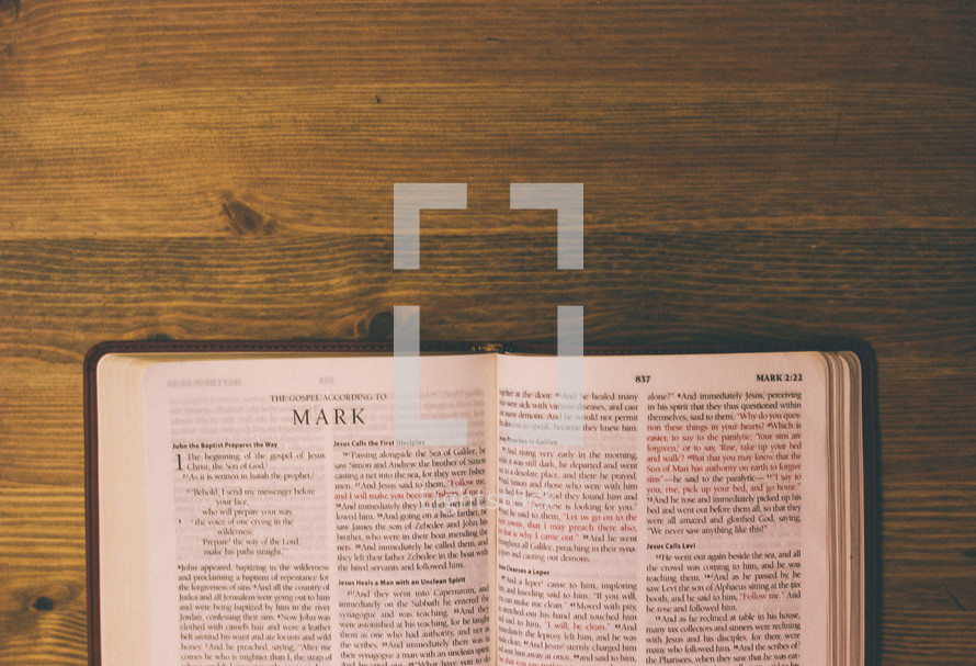 Bible open to Mark on a wooden table.