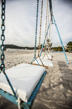 A swing set at a playground on the beach.