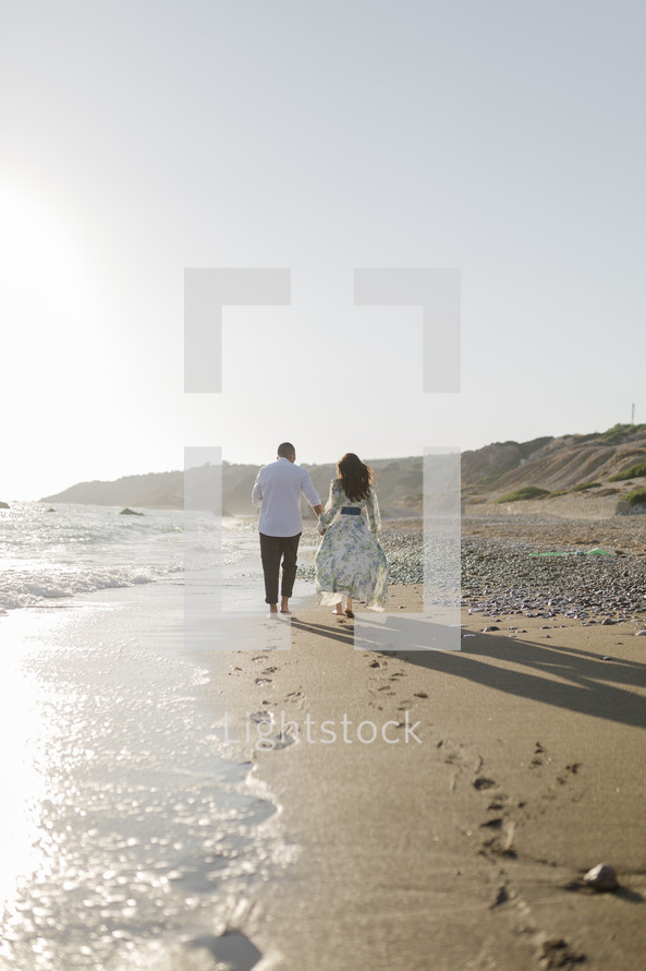Couple walking along the beach at sunset.