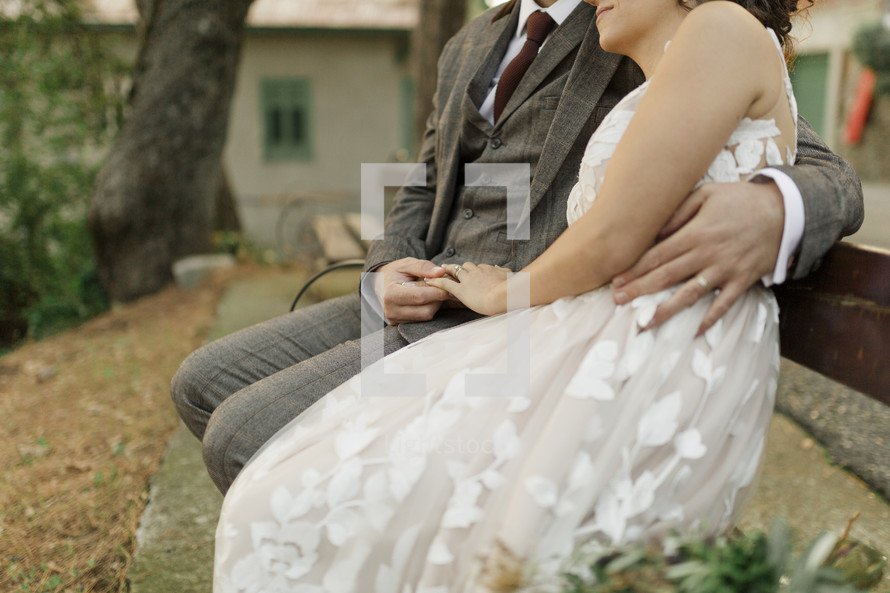  bride and groom sitting on a bench outdoors 