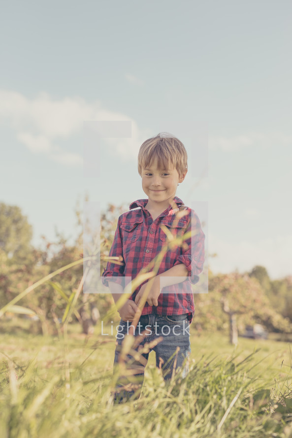 a boy playing in tall grass in fall 