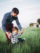a father walking in a field with his toddler son 
