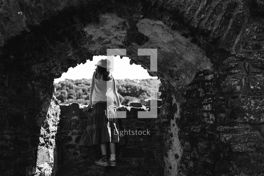 a girl looking through ruins 