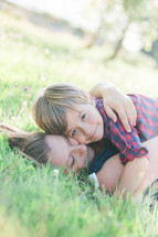 a mother and son hugging lying in the grass 