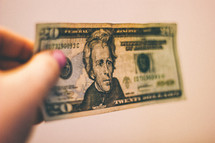 Hand holding a twenty dollar bill.