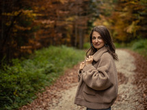 Woman with jacket posing on fall path
