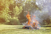 Bonfire outside in a grassy field.