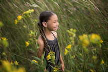 a girl walking through a field of tall grasses 