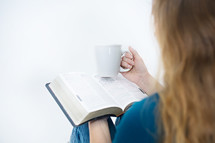 woman holding a mug of coffee and reading a Bible 