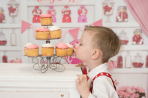 a toddler kissing cupcakes on a stand 