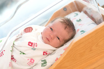 A newborn baby in a hospital crib.