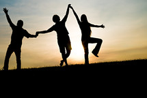 silhouettes of a father and his teenage children holding hands 