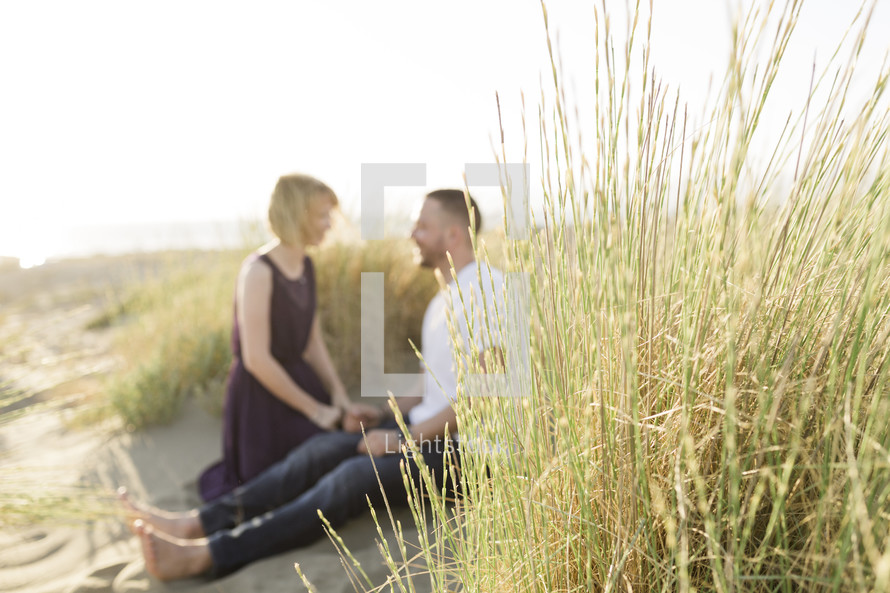 a couple sitting on sand dunes 