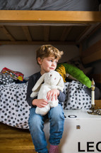 a sad child cuddling a stuffed animal 