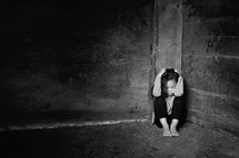 young scared girl hiding in a corner 