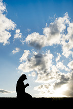 silhouette kneeling in prayer 