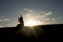 silhouette of a young girl with raised hands and a sunburst 