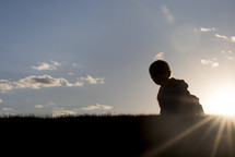 silhouette of a toddler in the grass 