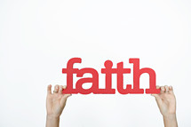 word faith in red held up by hands 