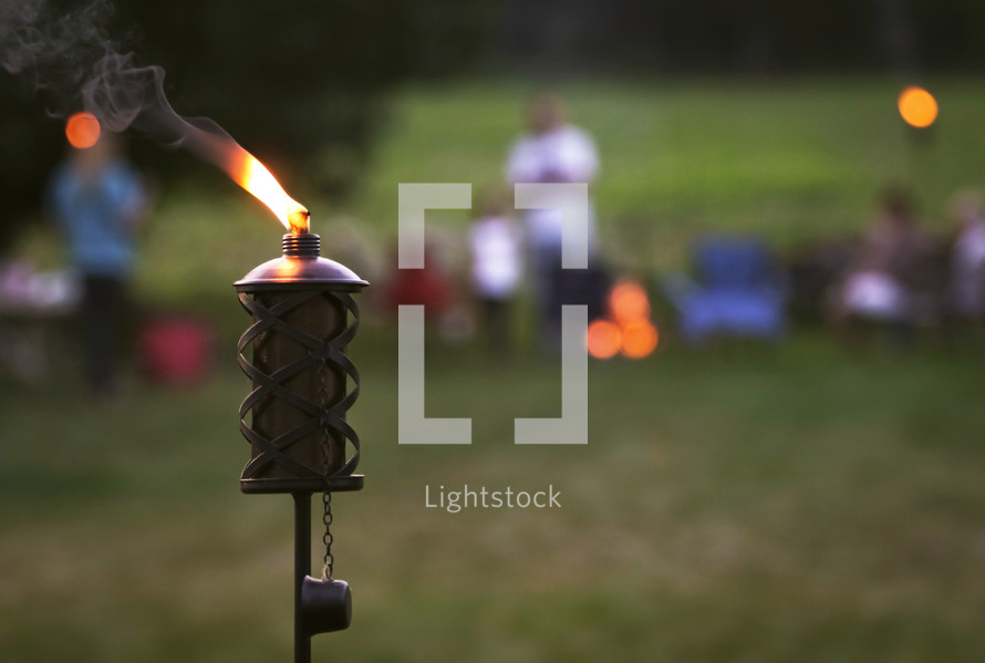 flames on a tiki torch at an outdoor summer party 