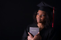 An African American woman graduate holding a Bible 