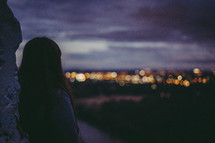 a woman looking out at city lights at night 
