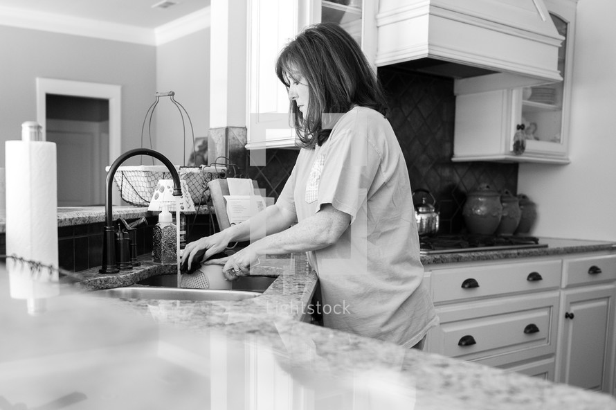 a woman washing dishes in the kitchen sink 