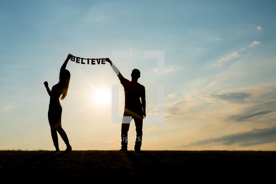 man and woman holding up the word Believe 