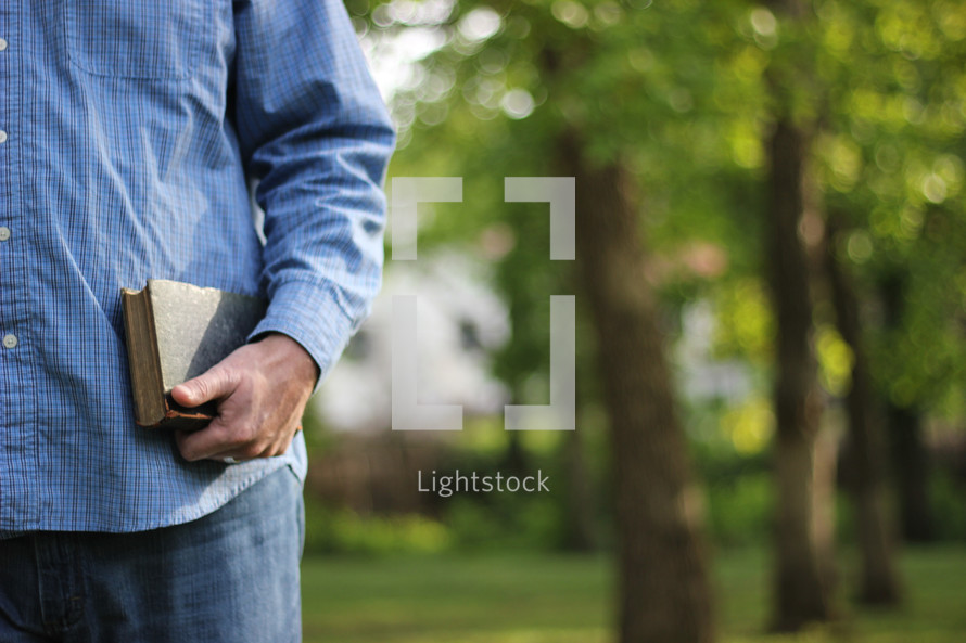Man standing outside holding a Bible.