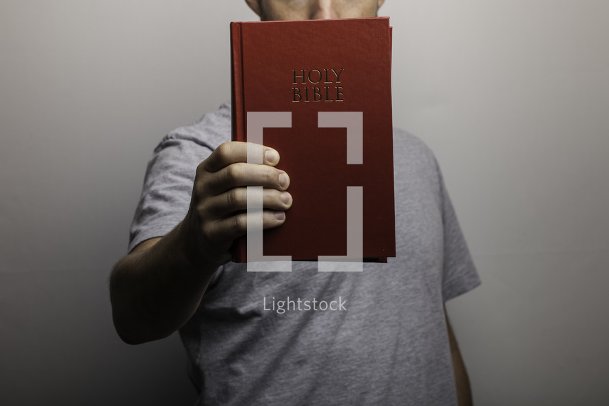 man holding out a Bible in front of him 