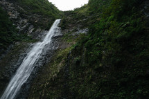 waterfall off the side of a green mountain 