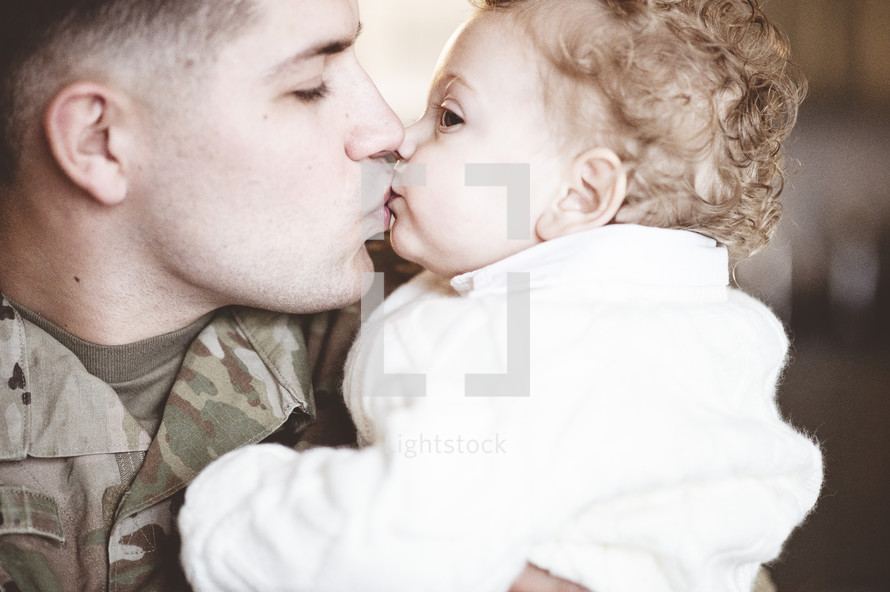 military dad kissing his toddler son 