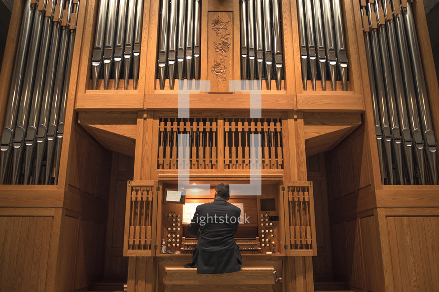 man playing an organ and organ pipes 