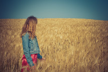 woman standing in a golden field of wheat 