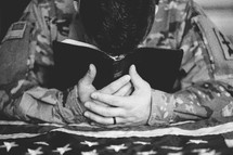 A serviceman praying with a Bible 