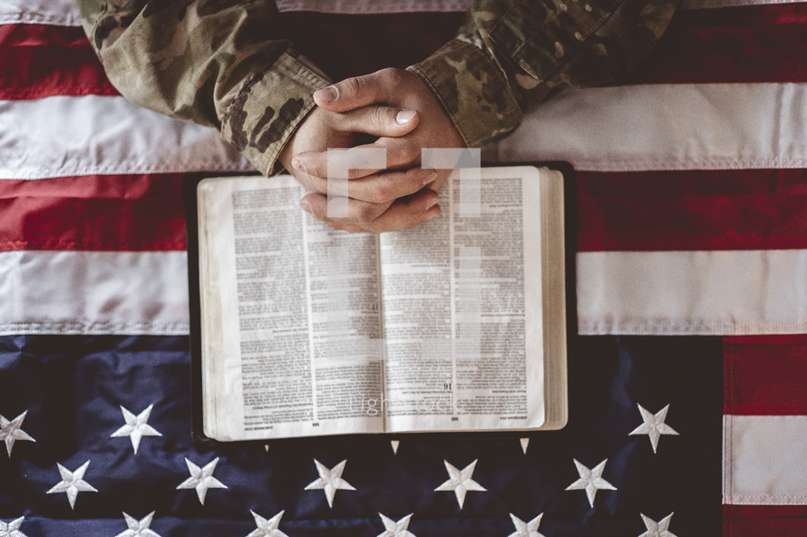 serviceman with praying hands over a Bible 