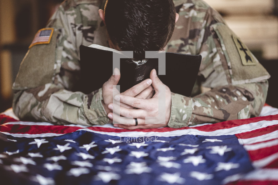 soldier praying with a Bible 