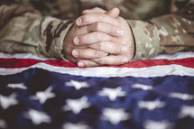 praying hands over an American flag 