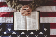 serviceman with praying hands over a Bible 