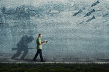 A man walks with a soldier shadow running towards battle