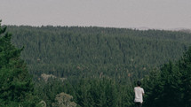 man looking out at a mountain forest 