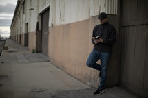 a man standing on a sidewalk reading a Bible 