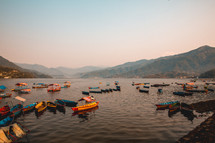 boats and mountains on a lake in Pokhara Nepal at sunset