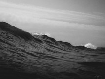 A black and white image of a wave beginning to break near the shore