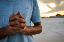 praying hands on a beach